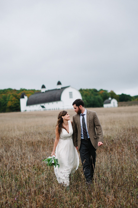 bride and groom walking though farm fields